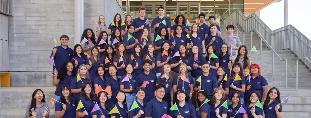 50 Orientation Team Leads pose with color mini flags.