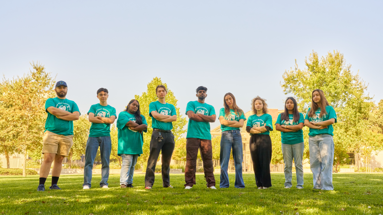 FYE team leads pose with arms crossed in a grassy field together.