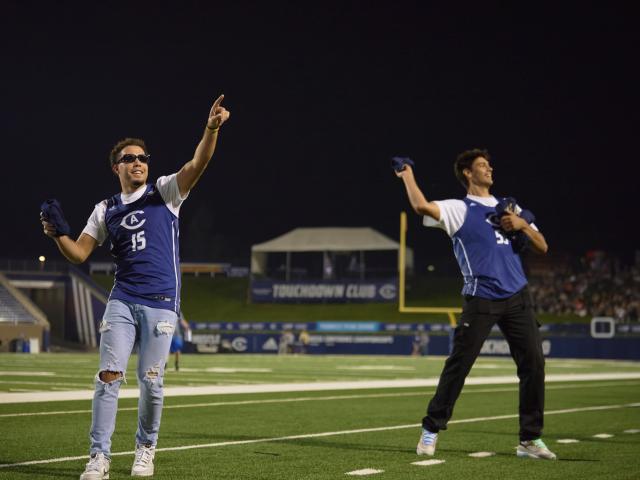 Football players through t-shirts to an out-of-view crowd.