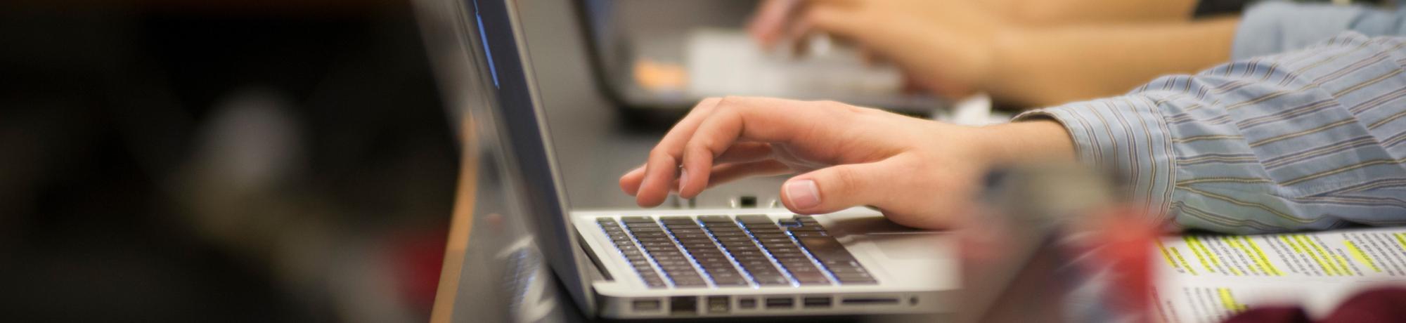 Students type on laptops.