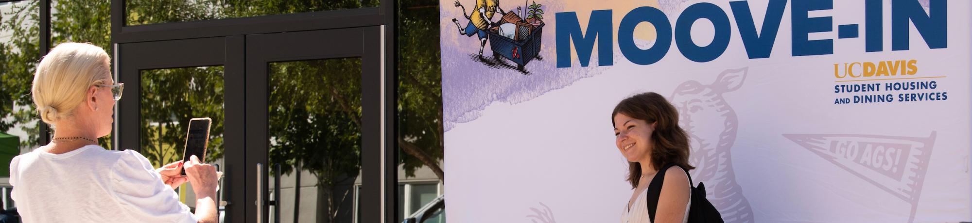 A parent takes a picture of their student moving into the dorms for Moove In Day