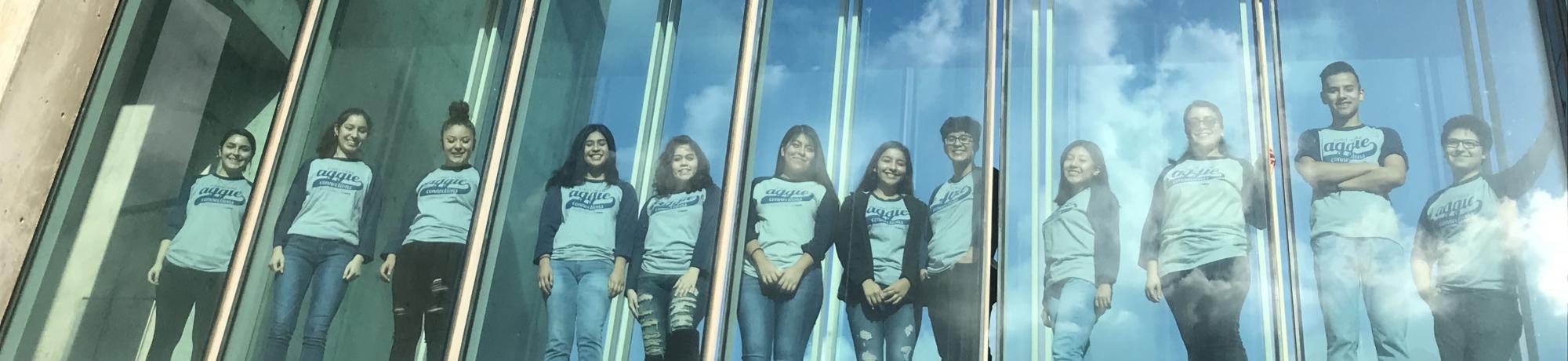students standing behind glass windows